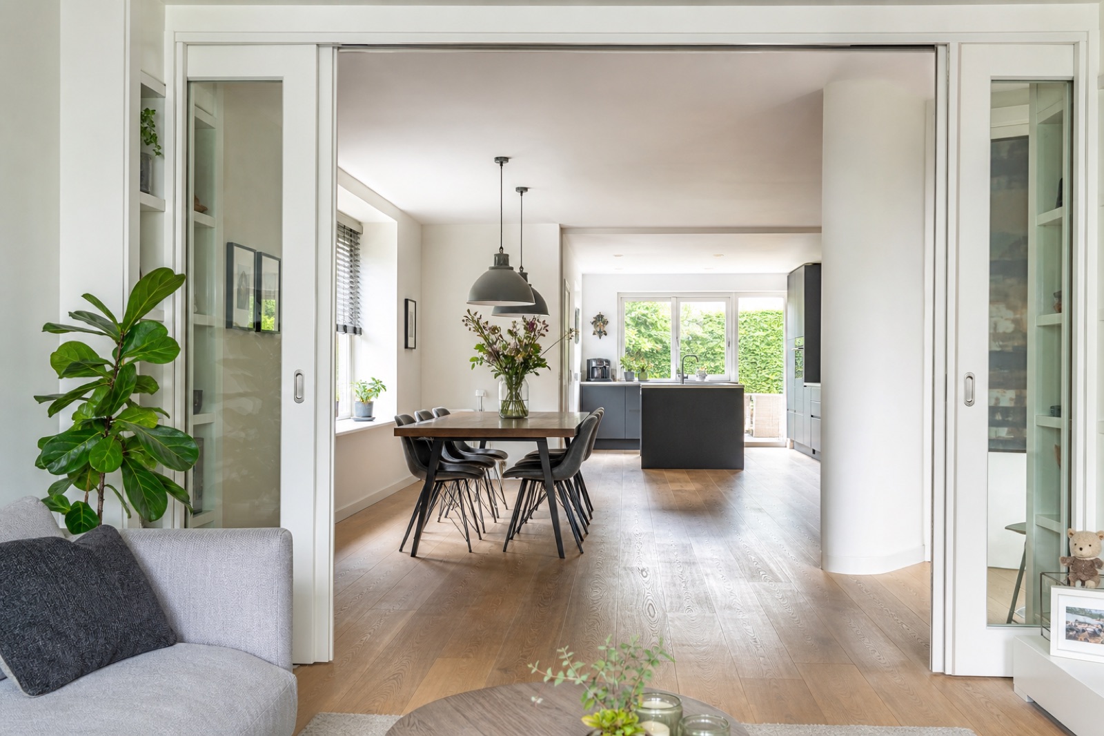 Doorkijk vanuit de woonkamer via open schuifdeuren naar de eetkamer en de keuken